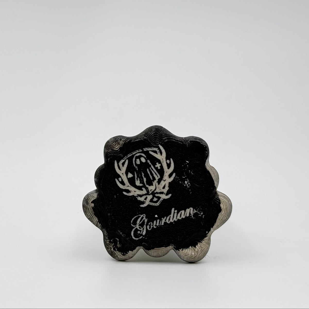 A hand painted folklore figurine made by The Nordic Ghost Merchants in Denmark. The image shows the base of the folklore ornament, painted black and engraved with the brand logo - a coat of arms with a sheet ghost in the centre