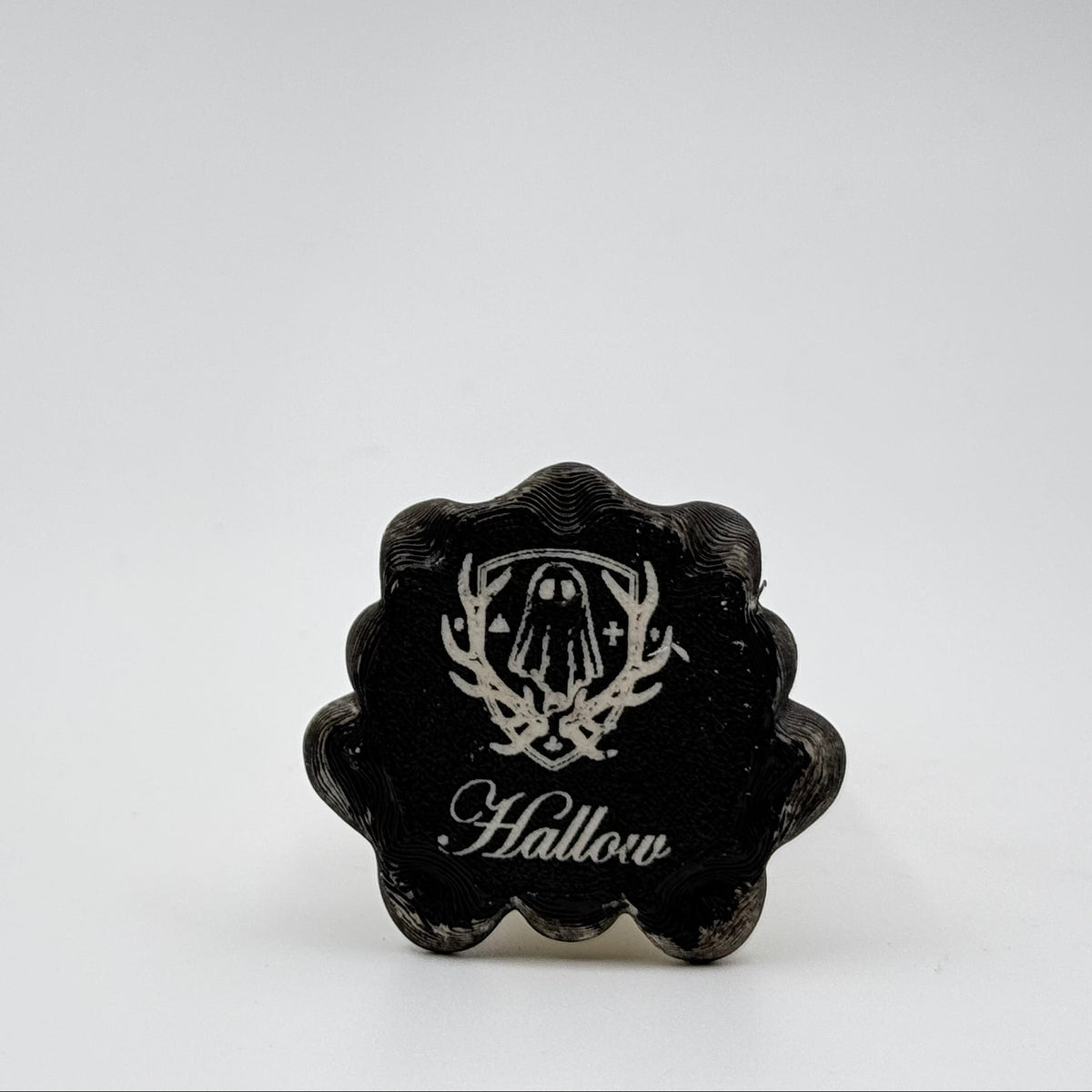 A hand painted folklore figurine made by The Nordic Ghost Merchants in Denmark. The image shows the base of the folklore ornament, painted black and engraved with the brand logo - a coat of arms with a sheet ghost in the centre.