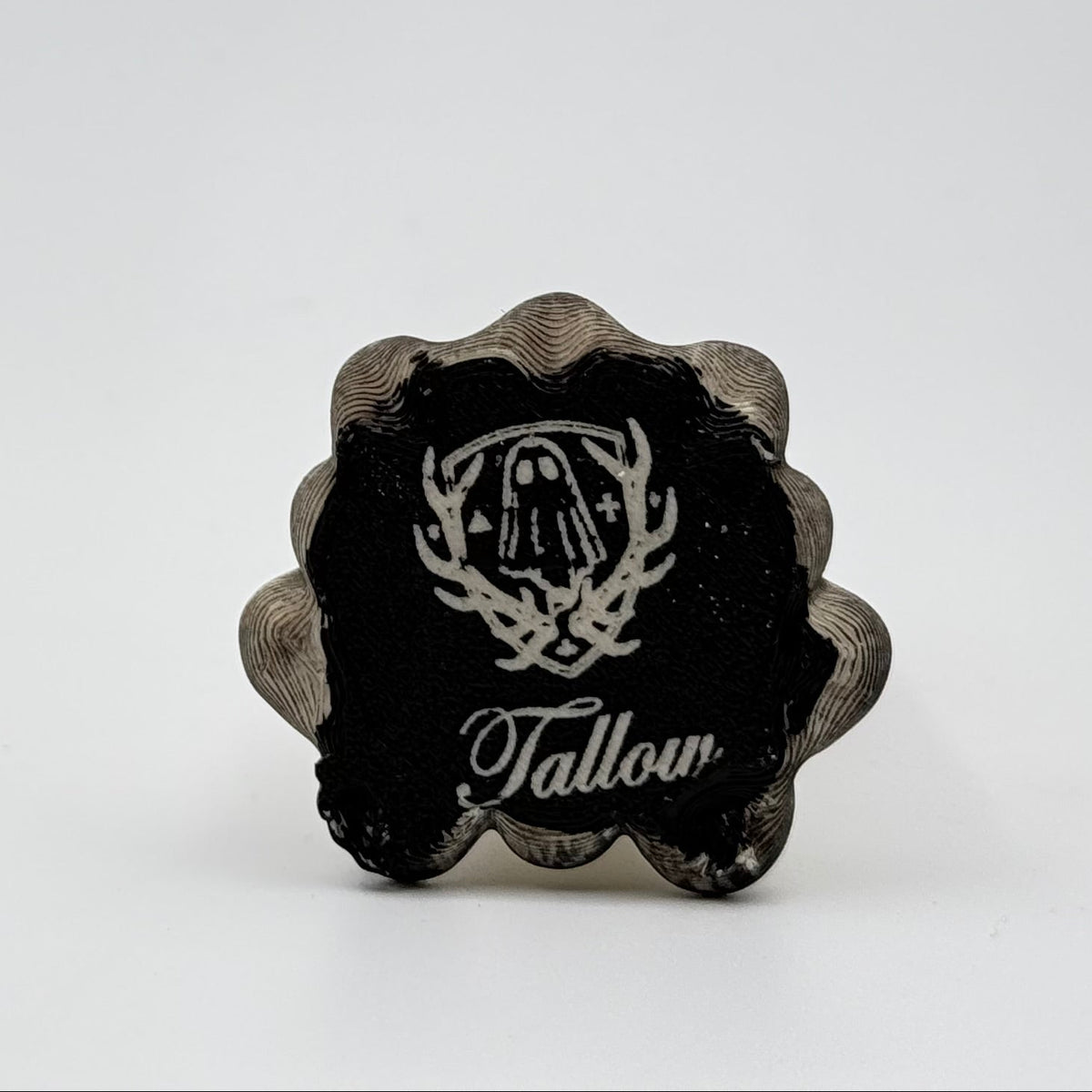 A hand painted folklore figurine made by The Nordic Ghost Merchants in Denmark. The image shows the base of the folklore ornament, painted black and engraved with the brand logo - a coat of arms with a sheet ghost in the centre.