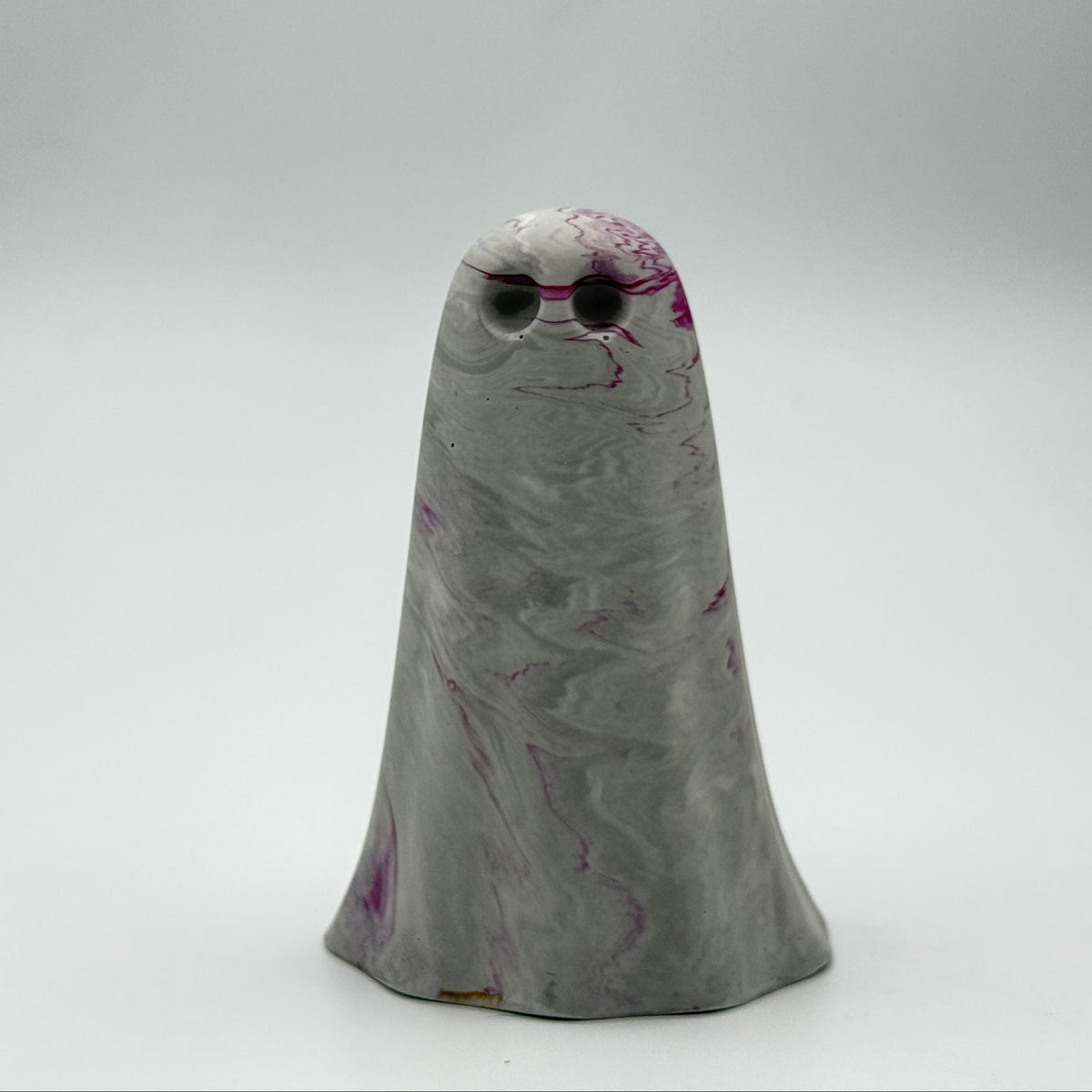 A grey and white marbled handmade ghost figurine made by The Nordic Ghost Merchants. The ghost has ripples of cerise pink throughout. Front view on a neutral grey studio background.