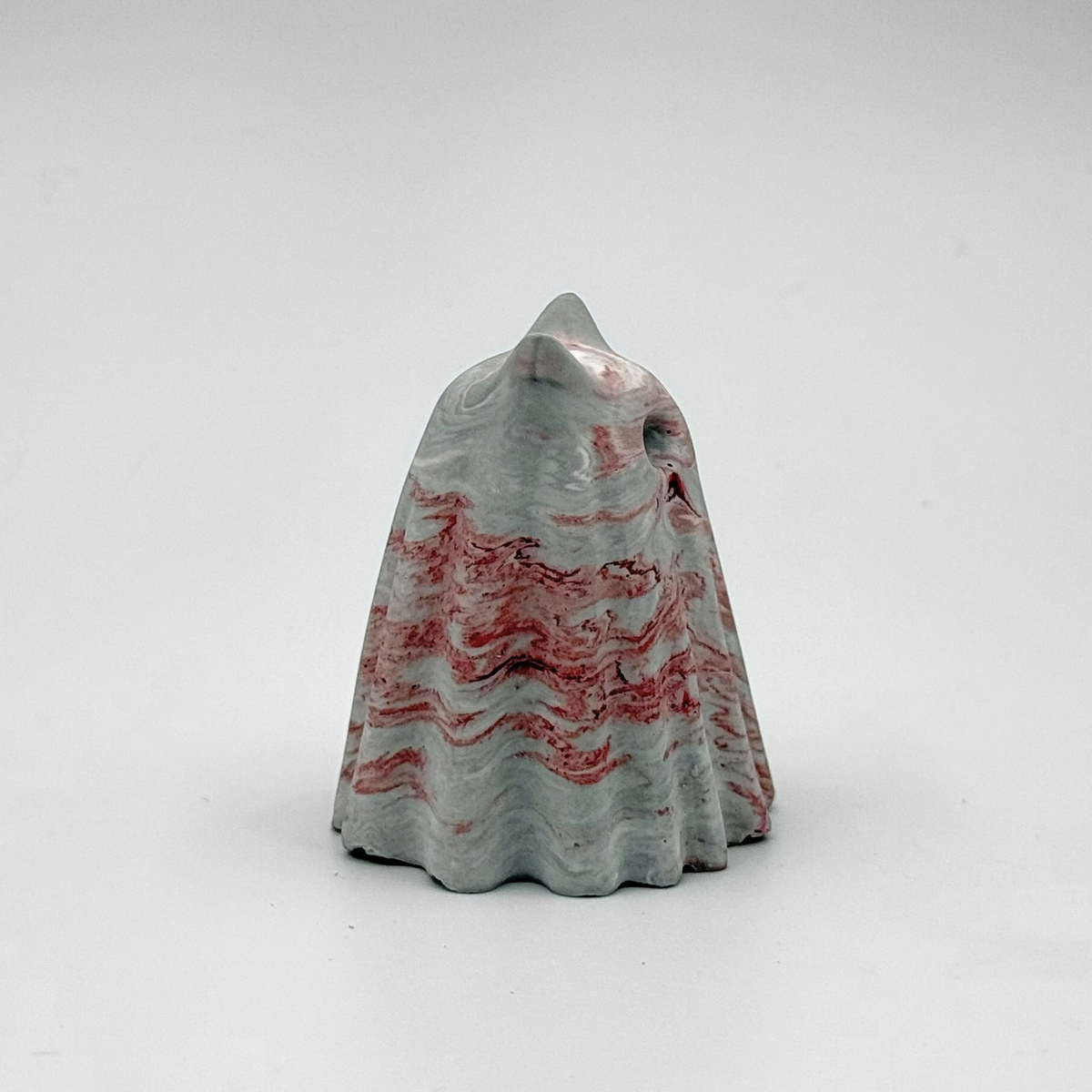 A small grey and white marbled ghost cat figurine, hand made by The Nordic Ghost Merchants. The ghost has red ripples running throughout.