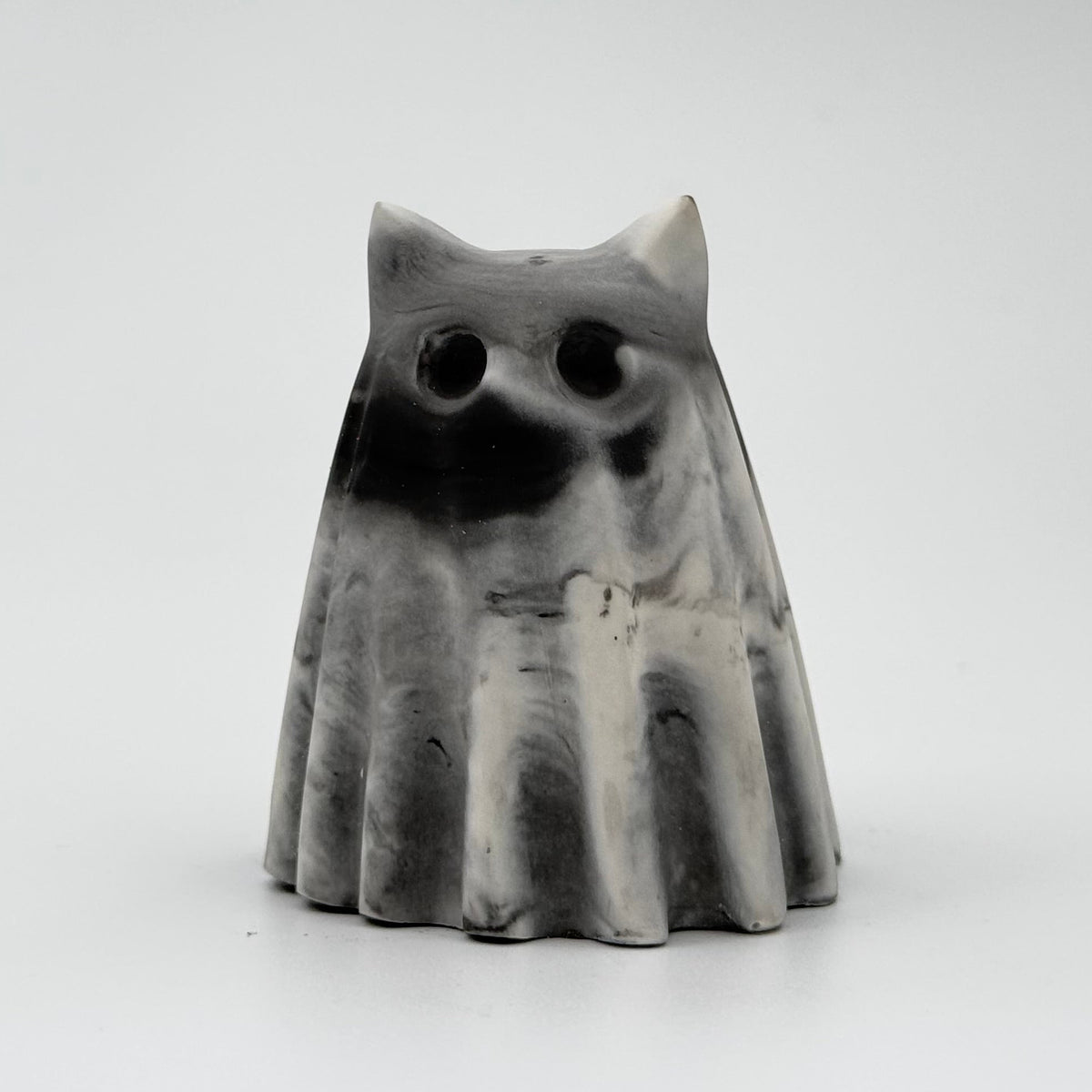 A grey and white handmade ghost figurine by The Nordic Ghost Merchants. The colours are smoky or fog-like. Front view on a grey studio background.