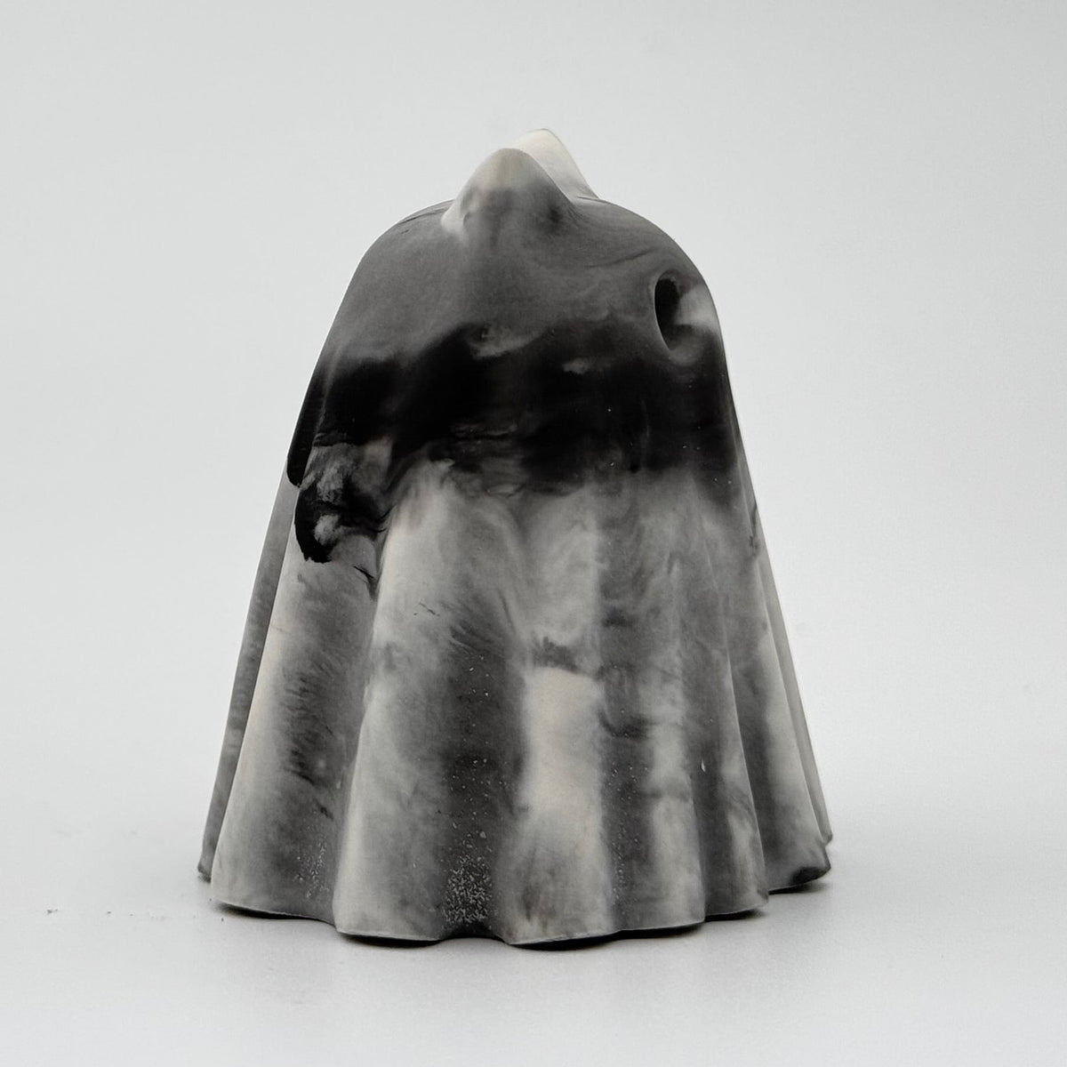 A grey and white handmade ghost figurine by The Nordic Ghost Merchants. The colours are smoky or fog-like. Side view on a grey studio background.