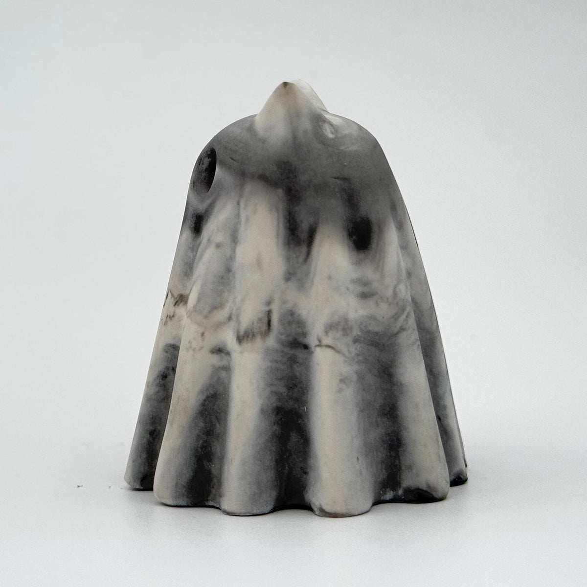 A grey and white handmade ghost figurine by The Nordic Ghost Merchants. The colours are smoky or fog-like. Side view on a grey studio background.