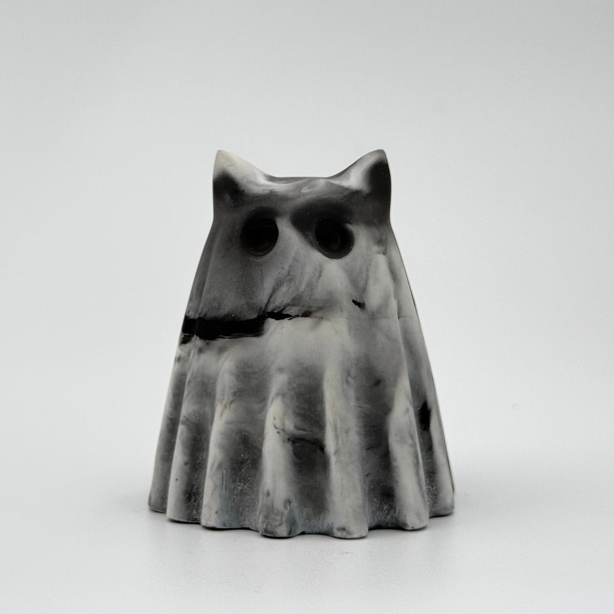 A grey and white marbled handmade ghost figurine made by The Nordic Ghost Merchants. The colours are in a smoky or fog-like design. Front view on a grey studio background.