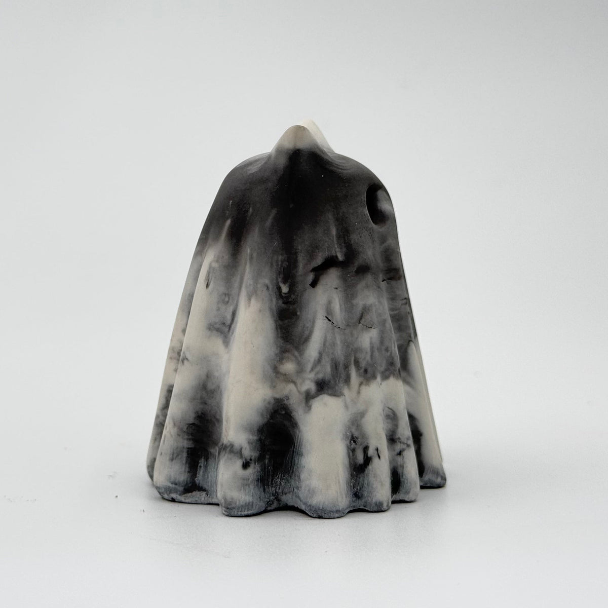 A grey and white marbled handmade ghost cat figurine by The Nordic Ghost Merchants. The colours are in a smoky or fog-like pattern. Side view on a grey studio background.