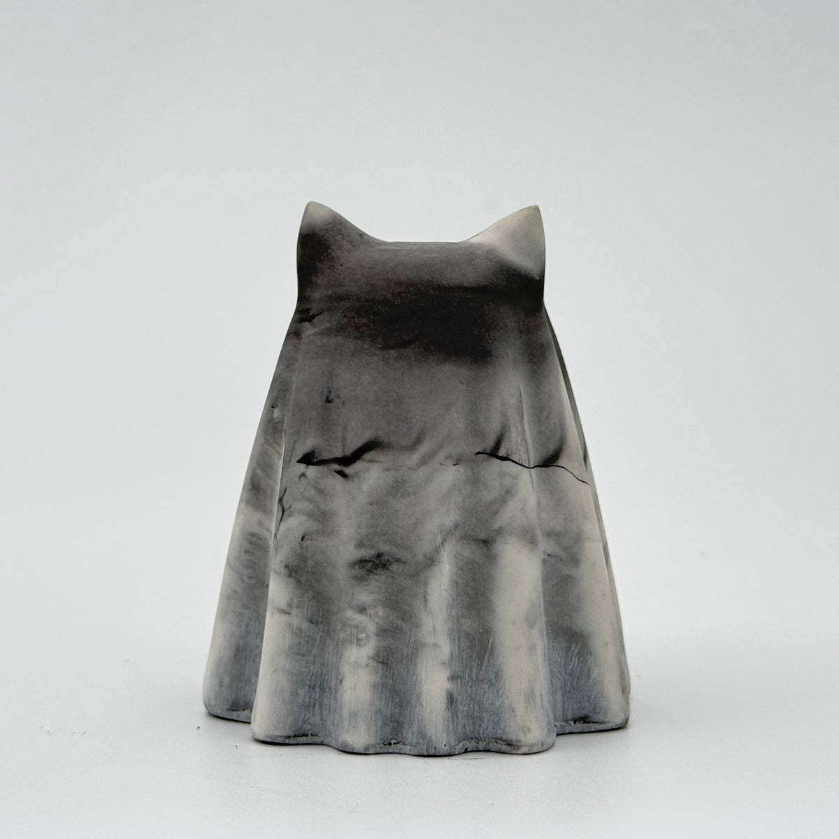 A grey and white marbled handmade ghost figurine made by The Nordic Ghost Merchants. The colours are smoky or fog-like. Rear view on a grey studio background.