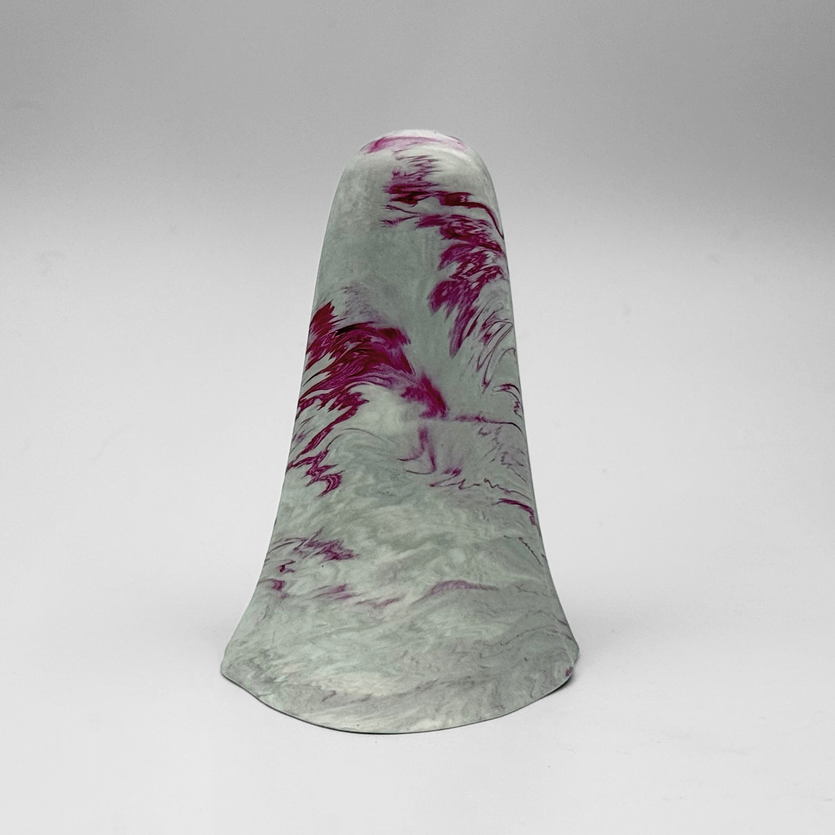 A white and grey marbled handmade ghost figurine by The Nordic Ghost Merchants. The ghost has cerise pink ripples running through it. Rear view on a grey studio background.