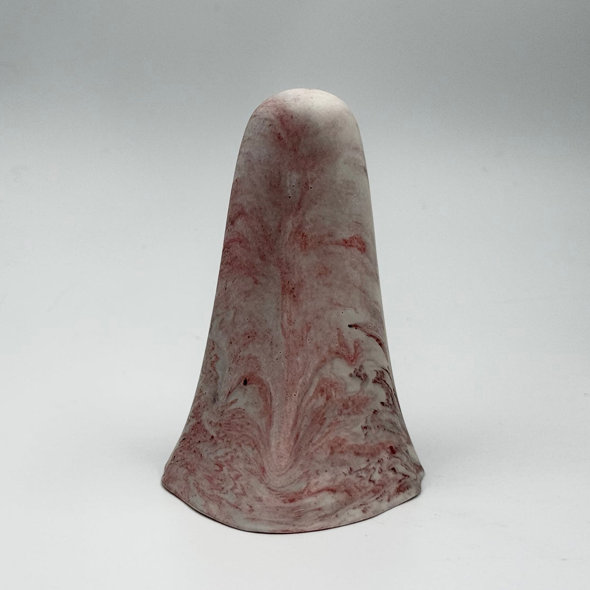 A small grey and white marbled handmade ghost figurine made by The Nordic Ghost Merchants. The ghost has dark red ripples throughout. Rear view on a grey studio background.