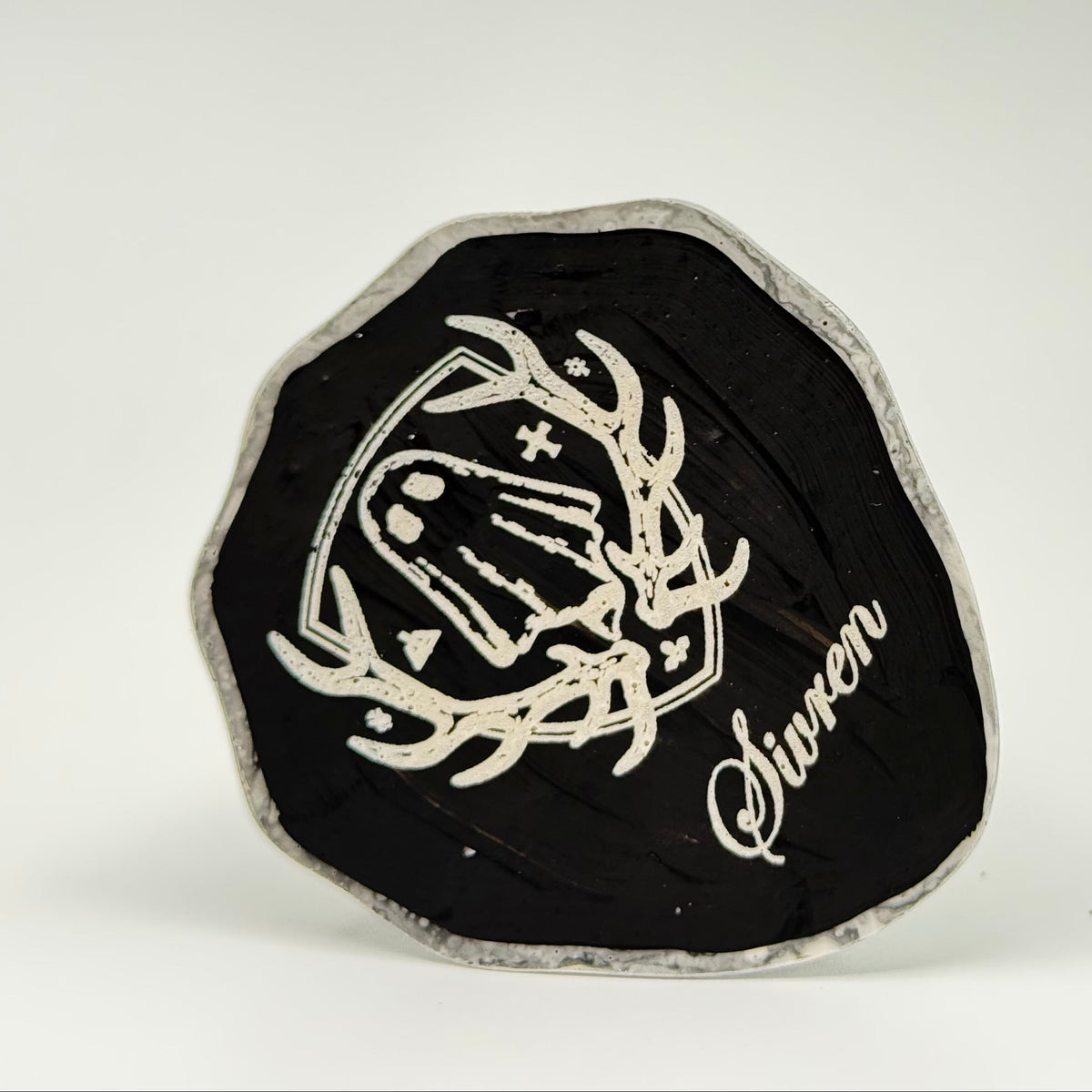 The base of a handmade ghost figurine, made by The Nordic Ghost Merchants. It is engraved with the brands coat of arms logo and the name of the ghost in italic script; Sivren