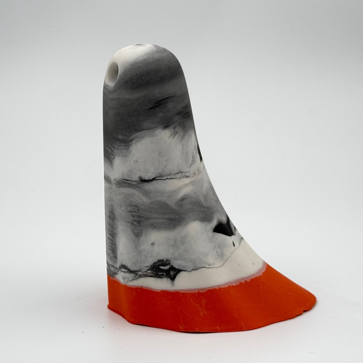 A handmade ghost figurine by The Nordic Ghost Merchants. The head and body of the ghost are a misty or smoky mix of grey and white. The bottom portion is a pumpkin orange shade. Side view on a grey studio background.